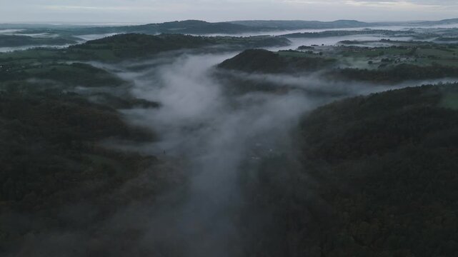 Aerial of hills and forest countryside in the fog