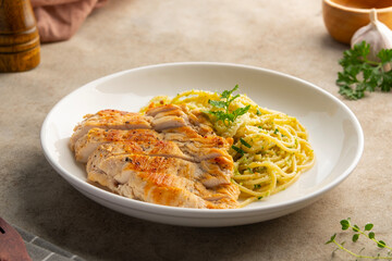 Grilled Chicken breast with spaghetti broccoli pesto sauce in a plate.