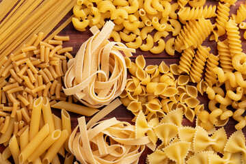 Various pasta on a dark wooden background.Uncooked Different types of pasta for background.