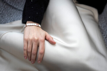 A white wooden bracelet with a red heart on the hand of an unrecognizable girl. Fragment.