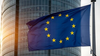 Flag of the european union waving in front of a modern glass office building at sunset or sunrise