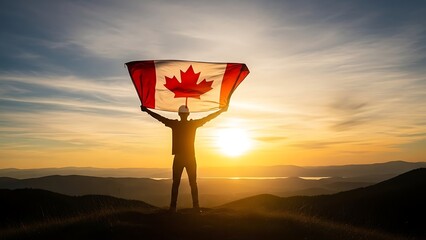Silhouette of a person holding a large canadian flag against a dramatic sunset over mountains