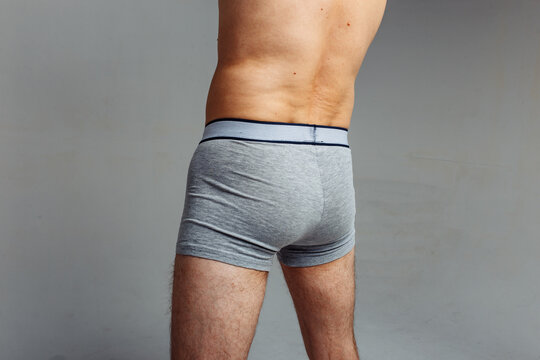 firm male ass in gray briefs. man standing with his back to the camera in underwear. concept: male health. loose skin on the lower back after diets and stress.