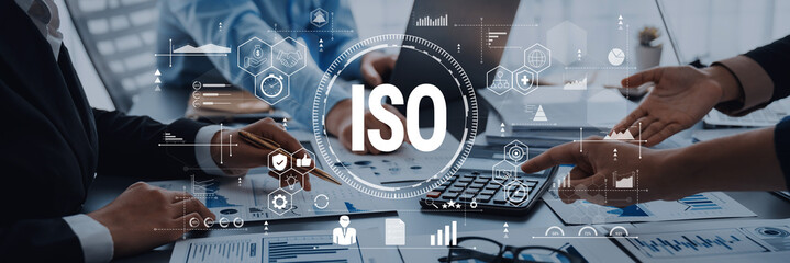 Business professionals engage in a dynamic discussion about ISO standards. The modern office setting showcases teamwork, technology, and strategic insights essential for growth. Trope