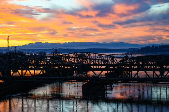 Colorful sunset over Olympic Mountains and road and rail bridges over Steamboat Slough