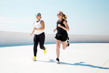 Women run together on a bright outdoor track