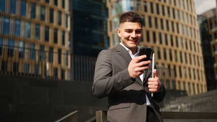 Businessman checks phone outside office building