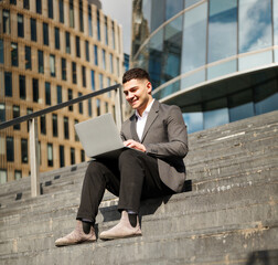 Man works on laptop while sitting on steps outside building