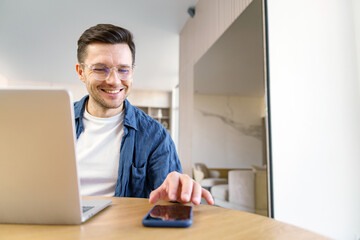 Man using laptop and phone in a modern space