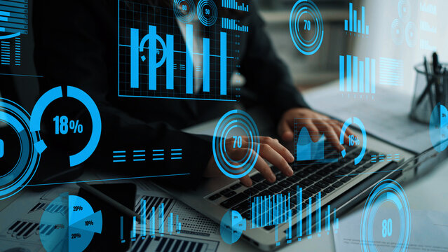 A focused professional analyzes data on a laptop, surrounded by digital graphs and charts, highlighting essential business statistics and insights in a modern office setting. Xenic - Powered by Adobe