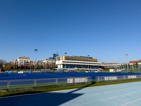 Poznan, Poland - November 18, 2025: Vibrant blue field hockey pitch and a light running track, with PZU Sport branding, beside a modern sports complex