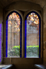 Elegant stained glass window framing vibrant autumn foliage in a historic stone building