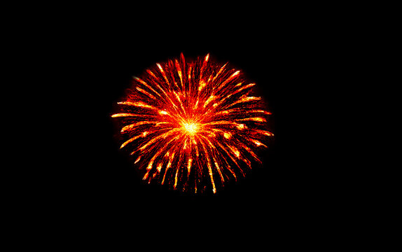 Spectacular single firework explosion illuminates dark night sky vibrant red orange colors radiating fiery light brilliant abstract holiday celebration event display show pyrotechnics