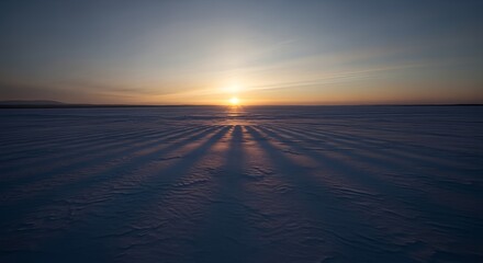 Wide panoramic view of a frozen snowy landscape during a sunrise with long shadows.