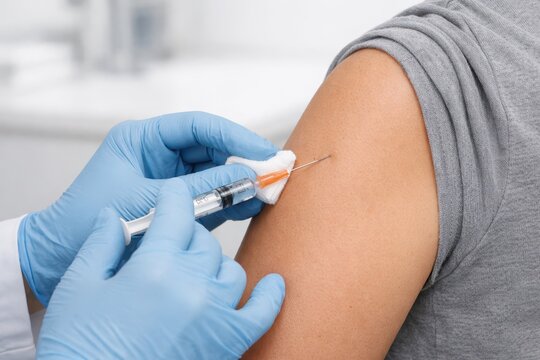 Vaccination Injection Administered By Healthcare Professional.
Close up of a nurse giving an injection in the upper arm using a sterile syringe.