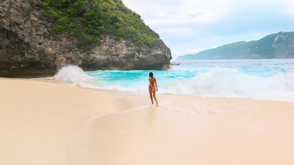 Woman On Secluded Tropical Beach With Waves And Cliffs In Bali Island