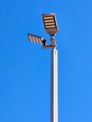 A modern street lamp against a clear blue sky, casting illumination