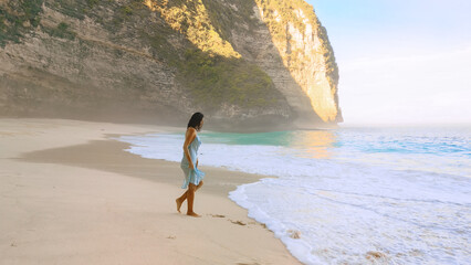 Woman Walking By Turquoise Surf At Kelingking Beach, Nusa Penida, Bali