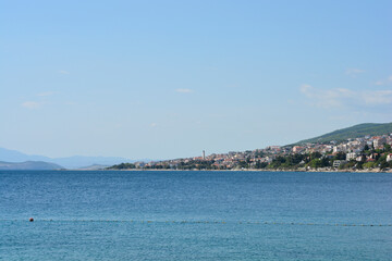 Fototapeta premium A coastal landscape showing the town of Crikvenica viewed from Selce along the blue Adriatic Sea with the Krk Bridge visible in the far distance under a clear sky.