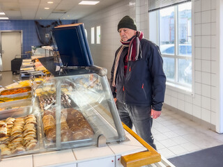 Healthy lifestyle concept with senior man choosing food at a fish store counter with prepared dishes on display, suitable for everyday shopping, senior lifestyle, nutrition and local fish market use.