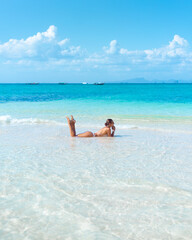 Back View Woman Sunbathing In Clear Turquoise Sea On Thai Island Beach