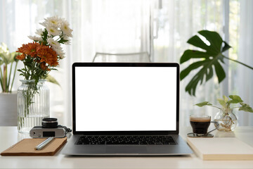 Laptop and brown notebooks and coffee cup, vintage camera and flowers vase on white table