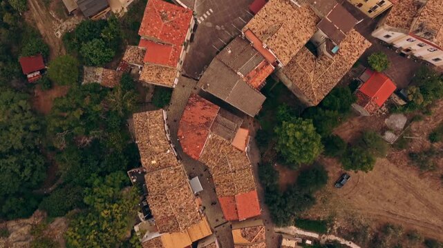 Aerial view of medieval Roccascalegna town glowing softly during golden hour under cloudy skies in central Italy.