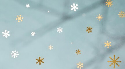 Floating snowflakes in white and gold against a pale blue background creating a wintery scene