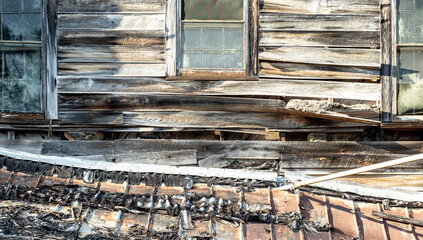 Detail shot of the wall and windows of an abandoned building with bleached and peeling paint.