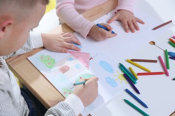 Children drawing with pencil and crayon at table indoors, closeup