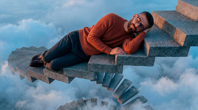 Man sleeping on a floating stone staircase above clouds