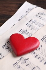 Heart figure and paper sheets with music notes on table, closeup