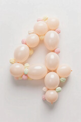 Number four made of pale color balloons and confeties, isolated on white background. realistic