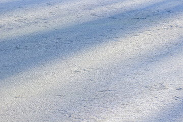 Frozen snow on the surface of ice. Shadows on the snow surface. Background