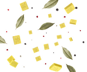 Bouillon cubes, dry bay leaves and peppercorns flying in air on white background