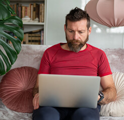 Bearded man working on laptop at home, remote work lifestyle
