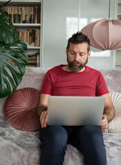 Bearded man working on laptop at home, remote work lifestyle