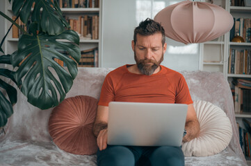 Bearded man working on laptop at home, remote work lifestyle