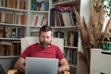 Bearded man working on laptop at home, remote work lifestyle
