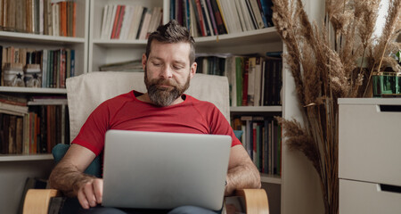 Bearded man working on laptop at home, remote work lifestyle