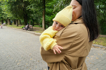 Mother Holding Baby in Yellow Outfit at Park early autumn