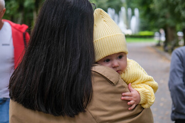 Mother Holding Baby in Yellow Outfit at Park early autumn