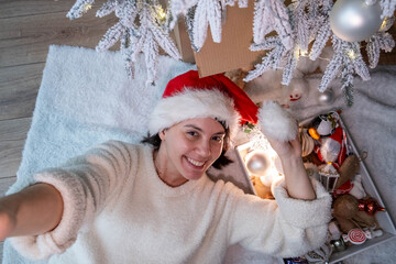 Smiling Woman in Santa Hat Enjoying Christmas Under Tree