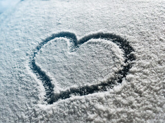 Valentine's Day concept: hand-drawn heart pattern on a frozen car windshield. Hand drawn heart shape on windshield of the car. Love symbol. Romantic background. A frozen windshield with a heart. 