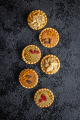 Sweet mini tartlets on black table. Top view.