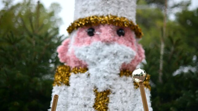 Decorative Christmas nutcracker soldier figure displayed outdoors with trees in the background