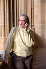 Soft sunlight highlights a woman in a cozy sweater talking on her phone in a historical setting during the afternoon