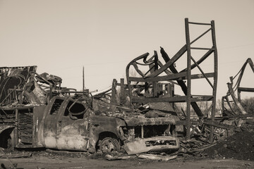 Destruction of vehicle and structure after fire at industrial site in morning light