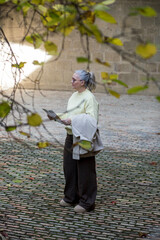 Exploring a quiet pathway, a woman with gray hair enjoys the serenity of nature on a cool afternoon