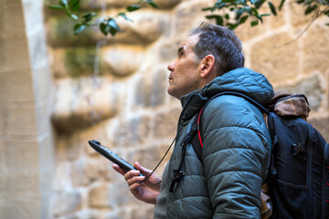 Explorer gazes upward in an ancient stone courtyard while holding a device